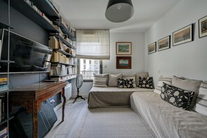 Ein modernes Schlafzimmer mit einem großen Bett, einem Holfnachtkästchen, einem Bücherregal und einem Deckenventilator.