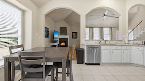 Una cocina moderna con armarios blancos, lavavajillas y un comedor con mesa y sillas.