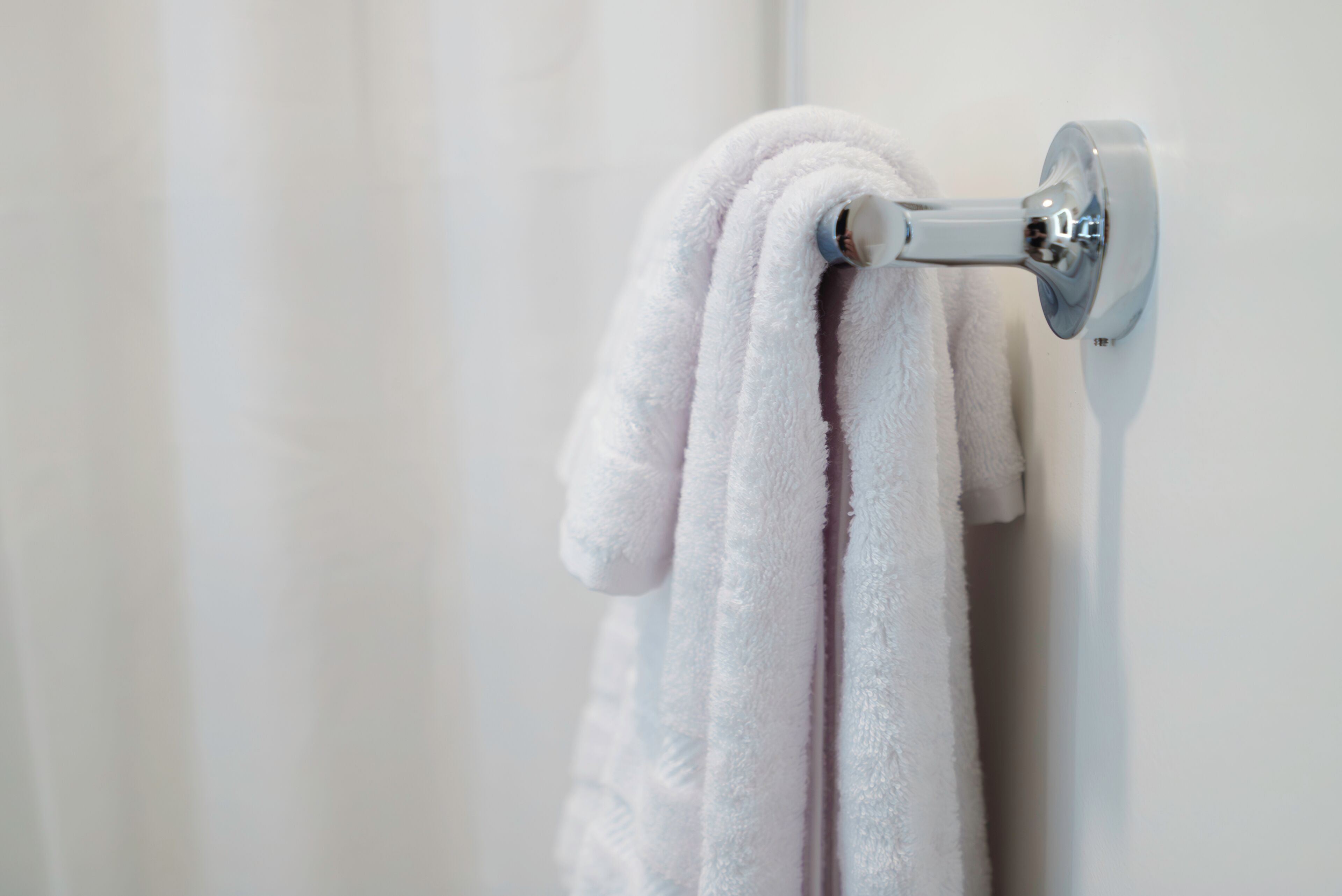 Une serviette blanche est suspendue à un porte-serviettes métallique fixé au mur.