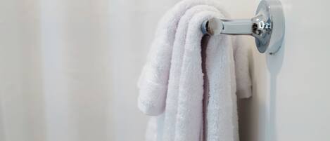 Une serviette blanche est suspendue à un porte-serviettes métallique fixé au mur.