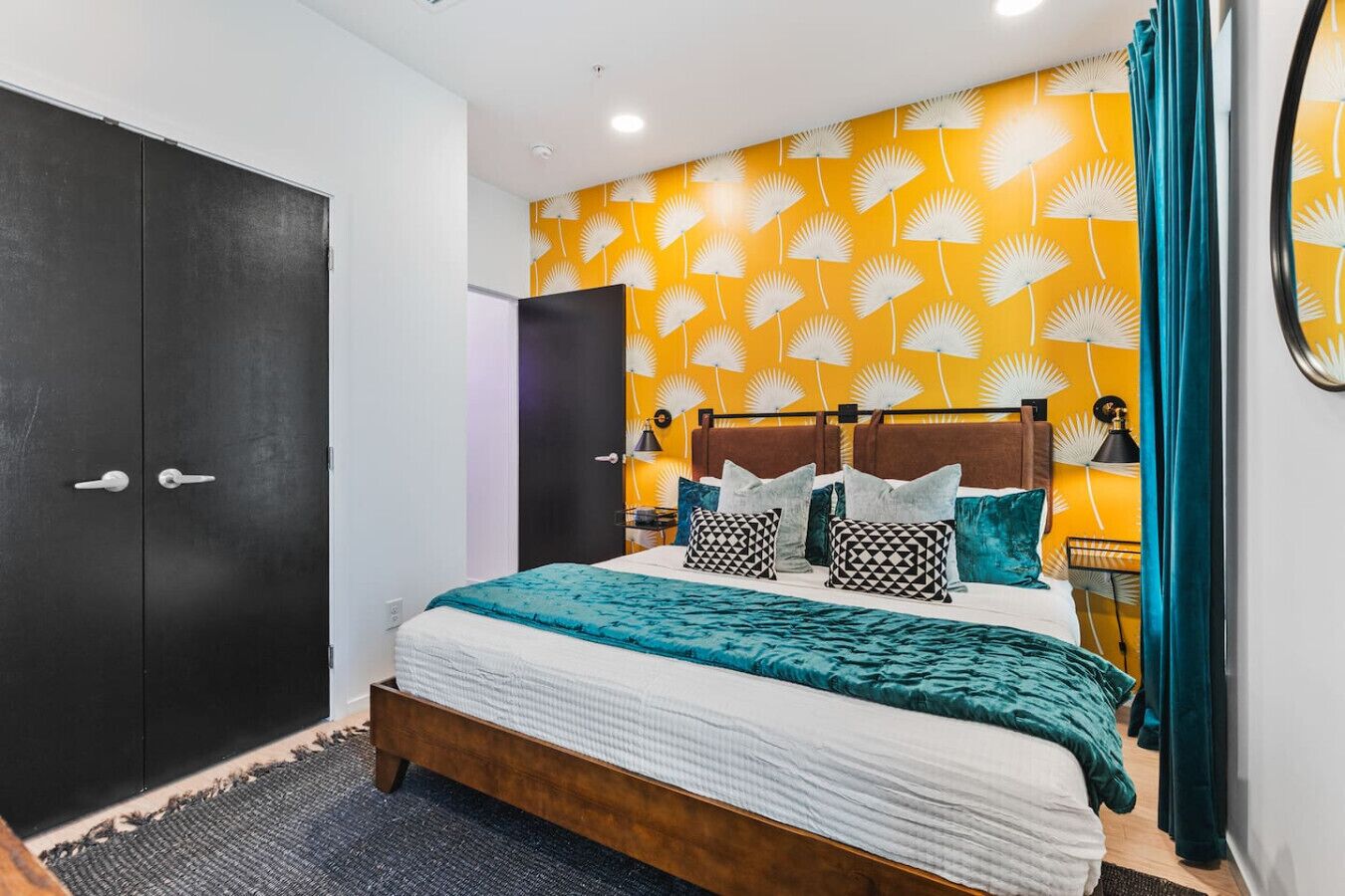 A modern bedroom with a bed, dark wardrobe, and a yellow wall with a fan pattern.
