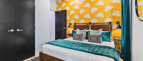 A modern bedroom with a bed, dark wardrobe, and a yellow wall with a fan pattern.