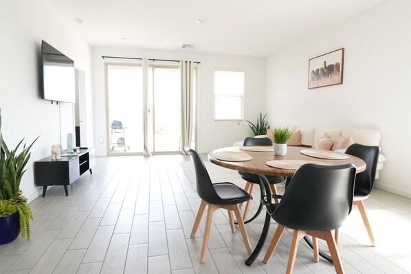 Een moderne eetruimte met een ronde tafel, zwarte stoelen en een potplant.