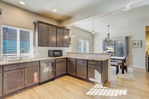 A kitchen with dark wood cabinets, a microwave, and a large island. - Westland Ridge! Modern Home in Historic Westside (Colorado Springs)