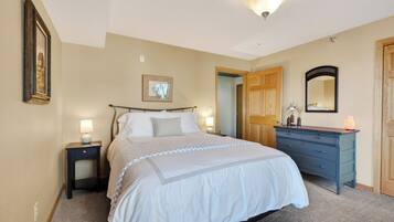 A bedroom with a bed, bedside tables, a dresser, a mirror, and a door.