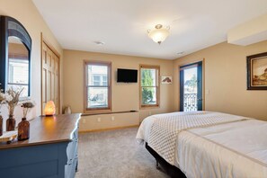 Ein Schlafzimmer mit Bett, Kommode und Fernseher an der Wand.