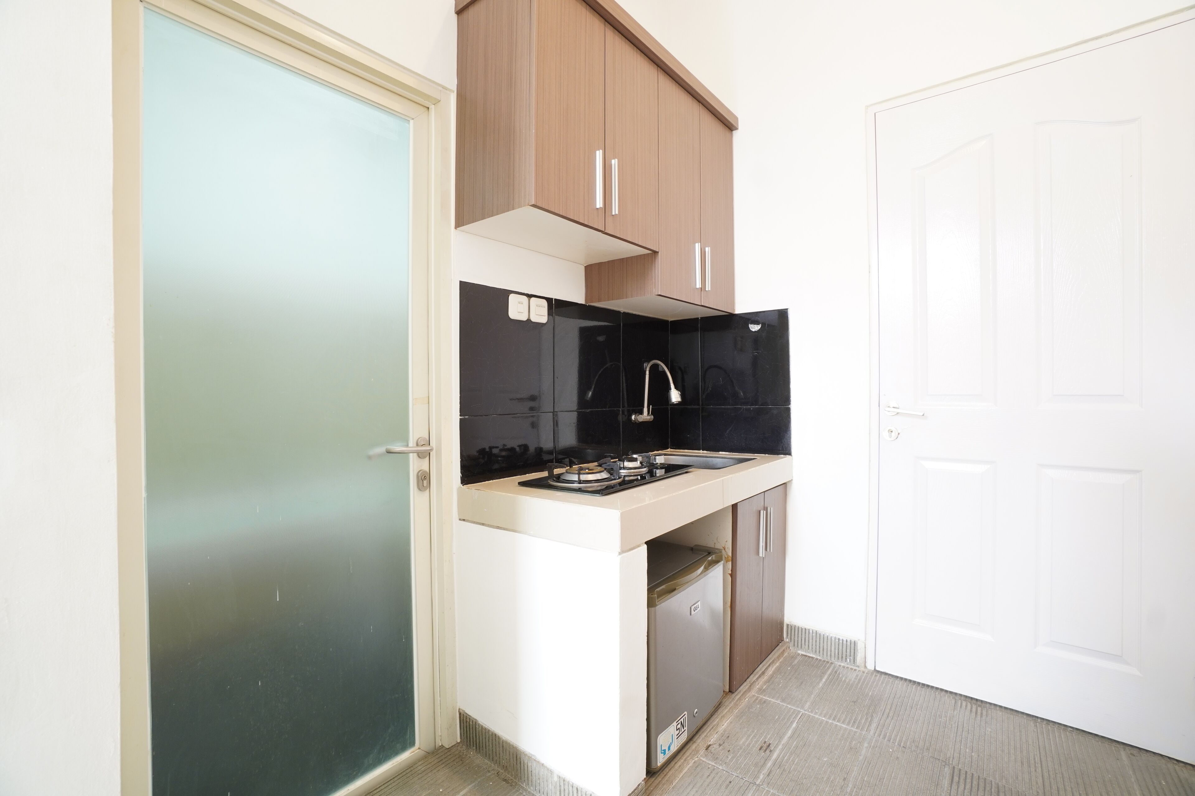 A compact kitchen with a gas stove, a sink, and wooden cabinets.
