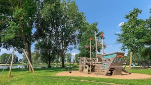 A wooden play structure with a pirate ship theme, surrounded by trees and a grassy area. - 3 bedroom nice home in Kerkdriel (Kerkdriel)