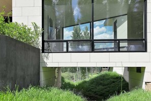 A modern building with large windows, a concrete retaining wall, and a grassy area.