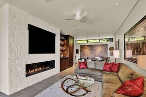 A modern living room with a fireplace, a sofa, and a flat-screen TV mounted on a textured wall.