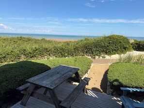 A wooden deck with picnic tables overlooking a beach. - Linger Longer by the Sea (Brewster)