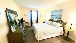 Quarto com cama, cómoda, televisão e um quadro na parede.