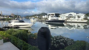 A marina with several yachts docked, surrounded by residential buildings and lush greenery.