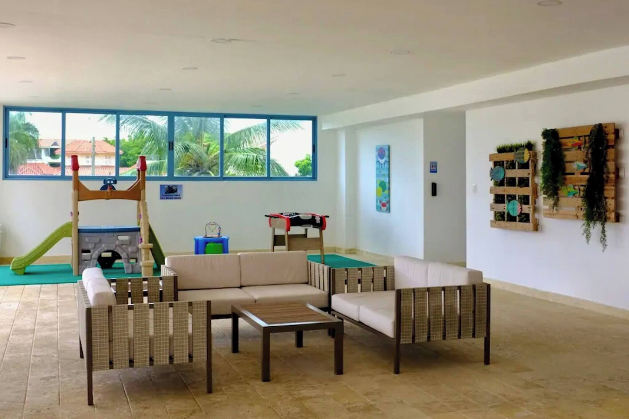 Una sala de estar con sofá, mesa de centro y una zona de juegos con tobogán y estructura de escalada.