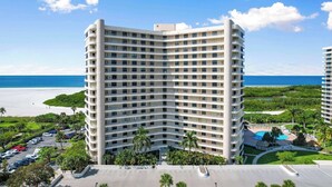 Een hoog hotel met meerdere balkons, een zwembad en uitzicht op het strand.