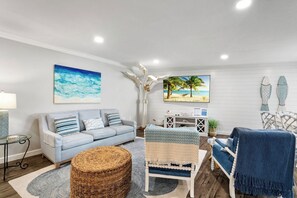 A living room with a sofa, armchairs, a coffee table, and artwork on the walls. - Saint Somewhere at Gulf Place 12 (Holmes Beach)