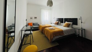 A modern hotel room with a bed, two bedside tables, a desk with a chair, a sofa, and a small table with a chair. - PORTAS RESIDENCE - LARGE APARTMENT - PONTA DELGADA CITY CENTER (Ponta Delgada)