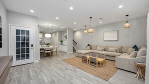 Una sala de estar moderna con un sofá seccional, una mesa de centro y una zona de comedor con una mesa y sillas.