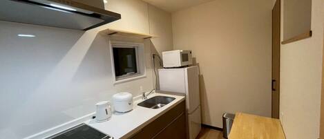 A compact kitchen with a built-in stove, a microwave, a sink, and a window.
