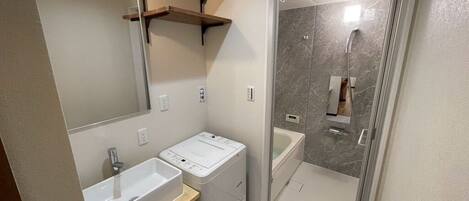 A modern bathroom with a built-in sink, a shower, and a mirror.