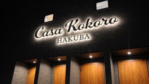 A hotel sign reading "Casa Kokoro Hakuba" with a modern design and wooden doors. - Casa Kokoro Hakuba (Hakuba)