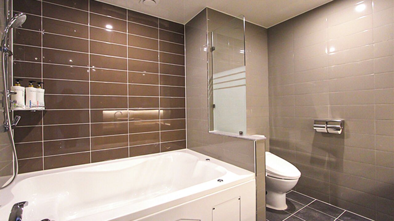 A modern bathroom with a bathtub, toilet, and shower area.