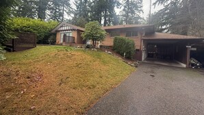 Una propiedad residencial con una casa de dos pisos, un garaje y un césped bien cuidado.