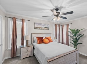 A bedroom with a bed, nightstands, a ceiling fan, and a window with curtains.