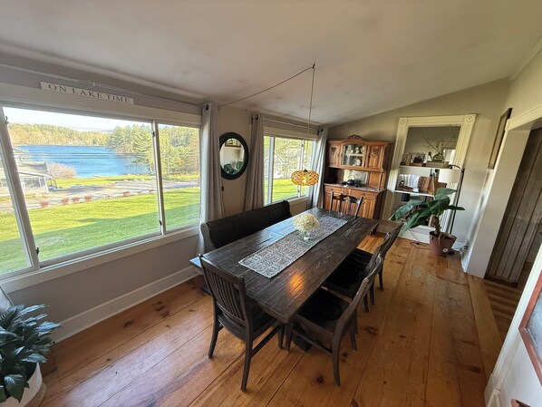 A dining area with a wooden table, chairs, and a view of a lake.