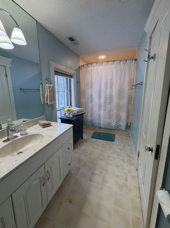 Une salle de bain équipée d’un lavabo, d’un miroir, d’un porte-serviettes et d’un rideau de douche.