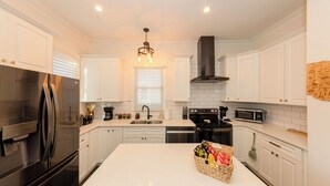 Une cuisine moderne avec des meubles blancs, des appareils en acier inoxydable et un îlot central.