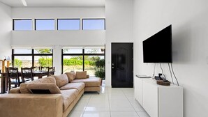A modern living room with a beige sectional sofa, a dining table with chairs, and a flat-screen TV mounted on a white cabinet. - Family Getaway with Private Pool | 15 Mins to Beach & Mount (Veintisiete de Abril, Guanacaste)