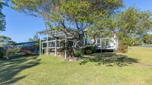 A house with a covered outdoor area, surrounded by a well-maintained lawn and trees. - Bendalong Beachside near Washerwomans Beach (Bendalong)