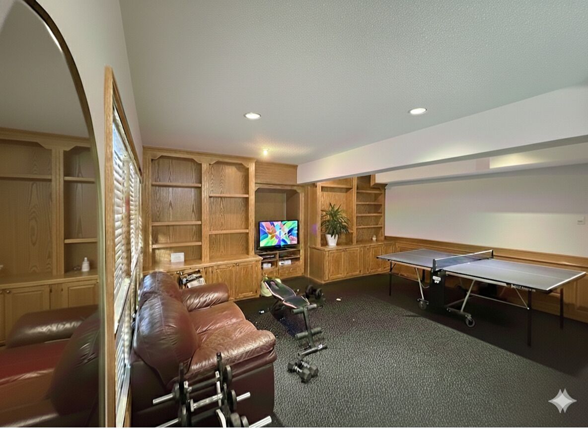 A room with a leather sofa, a massage chair, a ping pong table, and a TV.