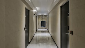 A modern hallway with a brick accent wall, a door with a number plate, and a light fixture on the ceiling. - Halfrest Hostel Jongno Insa (Seoul)