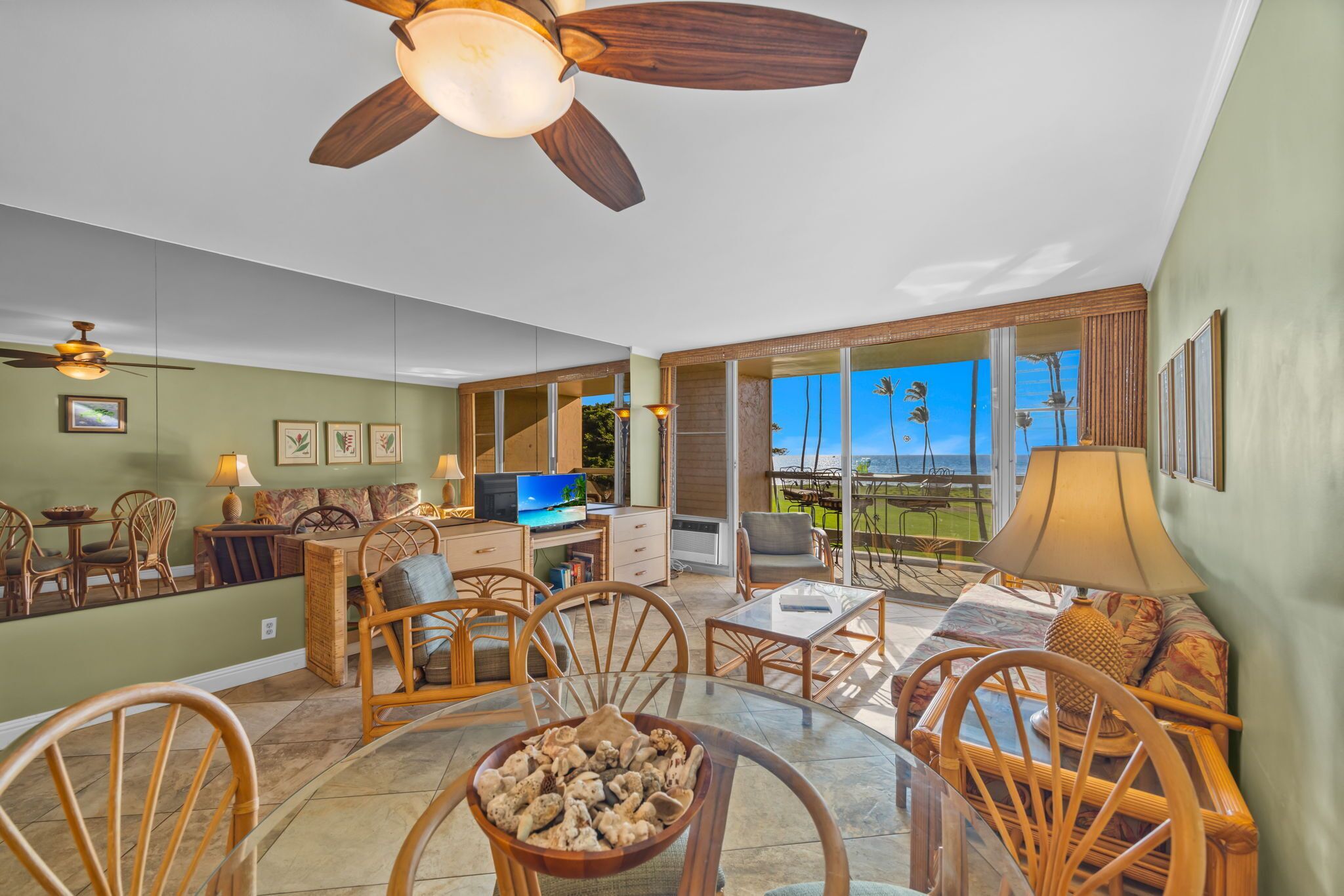 A spacious living area with a dining table, chairs, a television, and a large window offering a view of the outdoors.