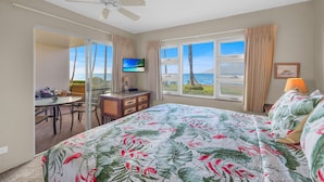 A bedroom with a bed, a TV, a desk, and a view of the ocean. - Stunning 2BR condo in South Kihei with ocean views! (Kihei)