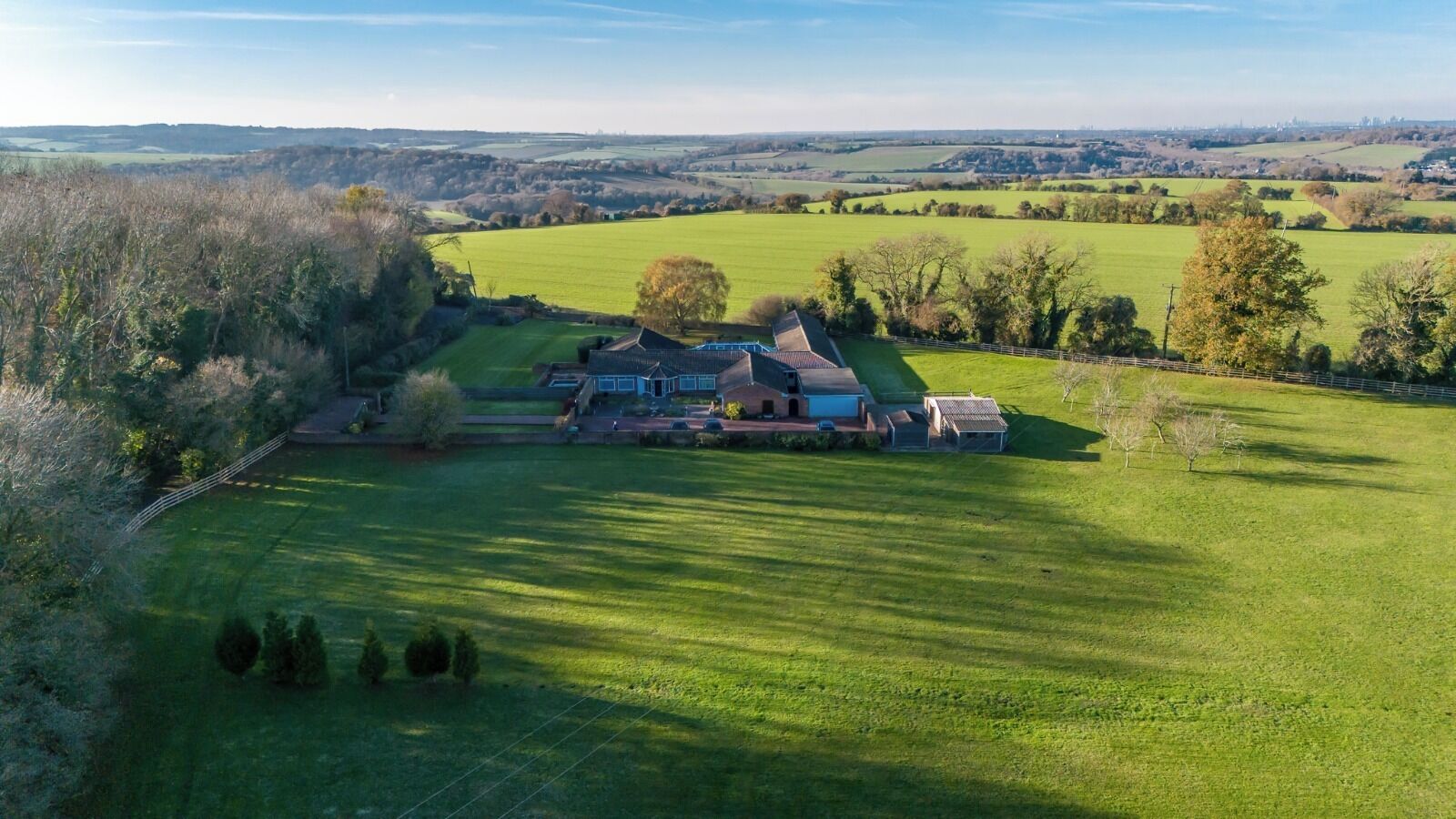 An aerial view of a large property with a main house, several outbuildings, and expansive green fields.