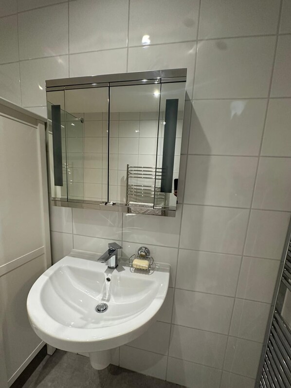 Ein Badezimmer mit einem weißen Waschbecken, einem Spiegel und einem Handtuchhalter.