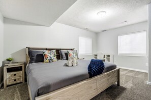 Ein Schlafzimmer mit einem Bett, einem Nachttisch, einer Kommode und einem Fenster mit Jalousien.