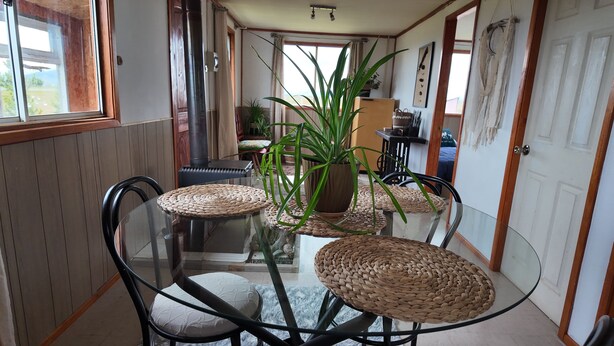 A dining area with a glass table, woven placemats, and chairs. - Dorotea Portal Cabin Puerto Natales Patagonia (Magallanes y la Antártica Chilena)