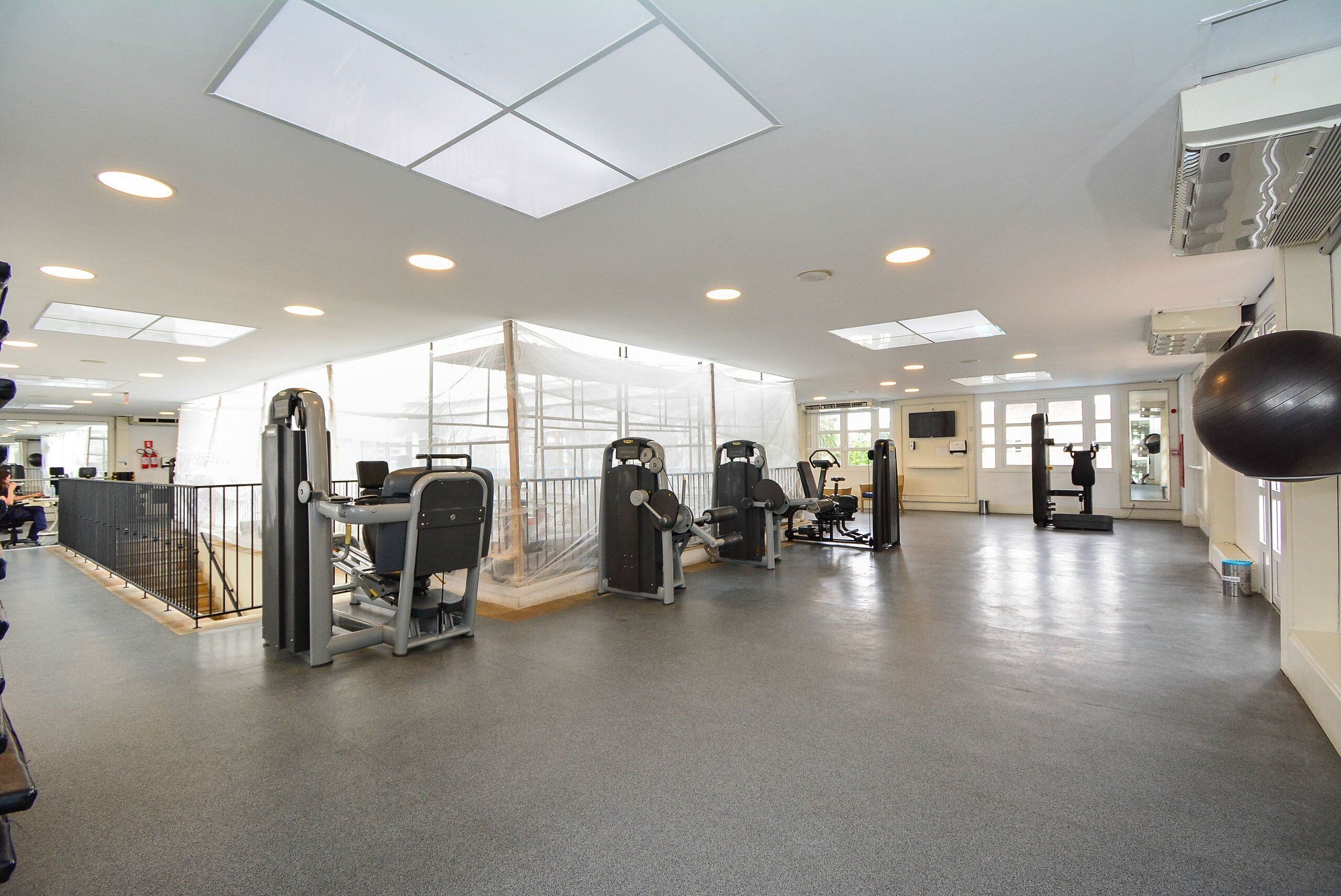 A gym with exercise equipment, a large mirror, and a ceiling with skylights.