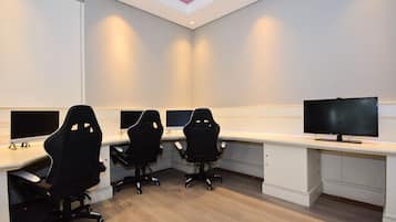 A conference room with three black office chairs, a large flat-screen TV, and a white desk.