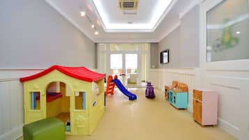 A children's play area with a slide, playhouse, and storage cabinets.