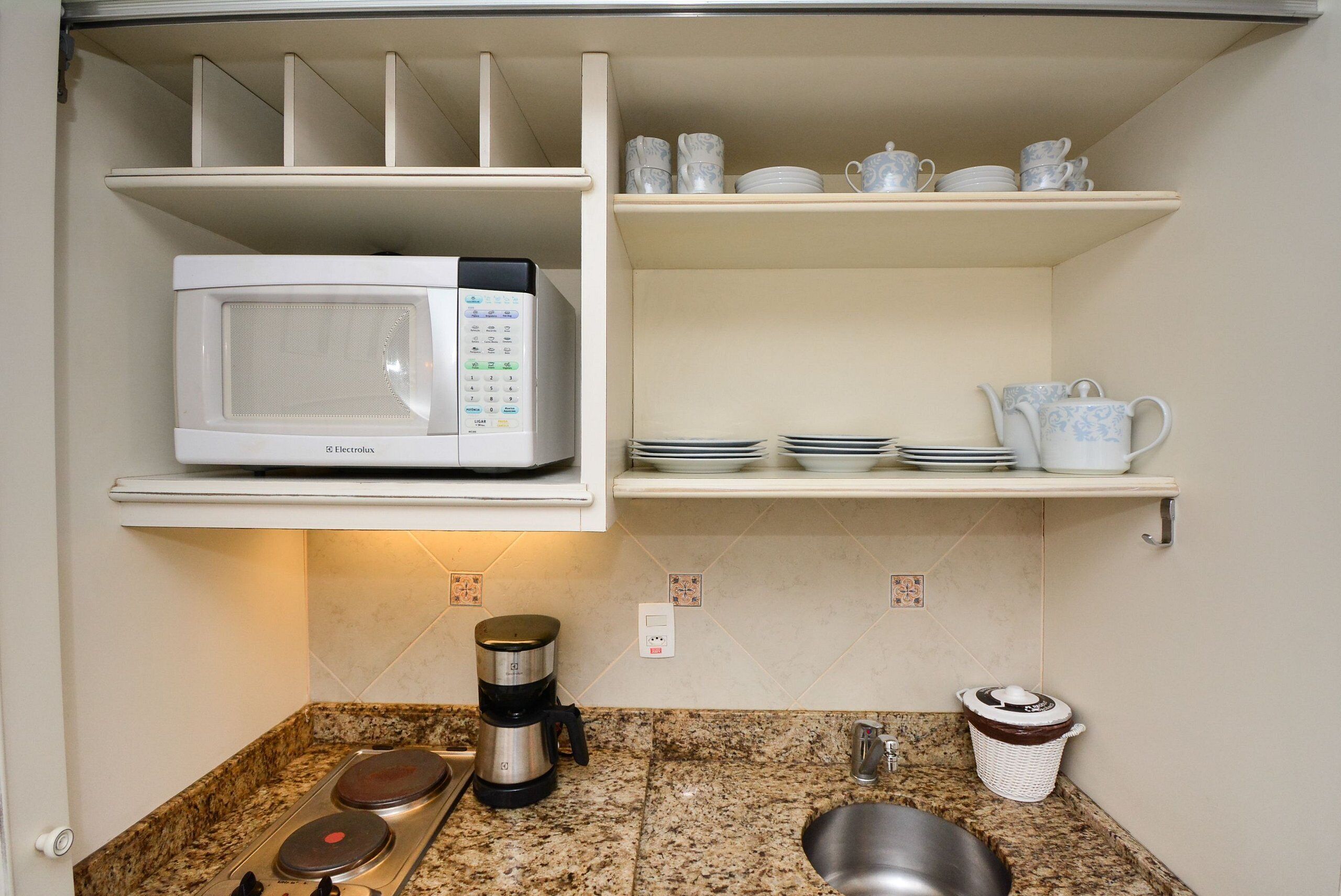 A kitchen with a microwave, coffee maker, and a sink.