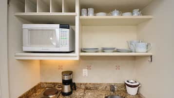 A kitchen with a microwave, coffee maker, and a sink.