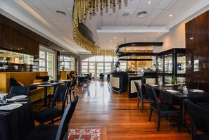 A restaurant with a bar area, wooden flooring, and a modern ceiling design. - IL CAMPANÁRIO (Florianópolis)