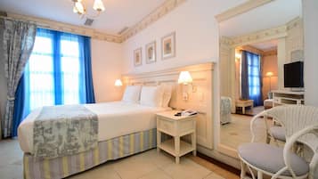 A hotel room with a bed, bedside table, chair, and a mirror.