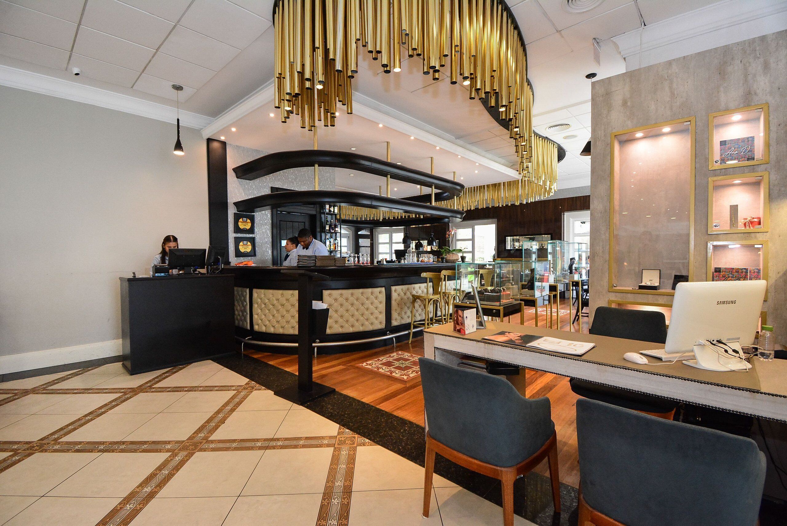A modern hotel lobby with a reception desk, seating area, and a bar.