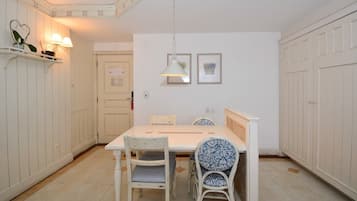 A dining area with a white table, two chairs, and a hanging light fixture.